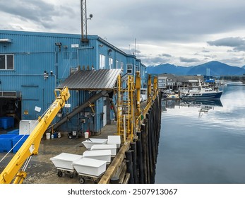 Elevated dock for loading and unloading at a seafood processing plant along a harbor waterfront on an overcast morning in Sitka, Alaska, early in summer, for industrial motifs of the Pacific Northwest