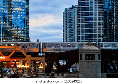Elevated "el" train during evening commute at sunset as seen from Upper Wacker Drive in Chicago Loop while commuters hurry home.