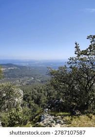 Elevated mountain viewpoint overlooking expansive green valley under clear sky.