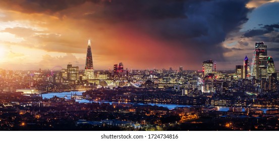 Elevated, panoramic view to the lit skyline of London, United Kingdom, during sunset time with colorful clouds and rain - Powered by Shutterstock