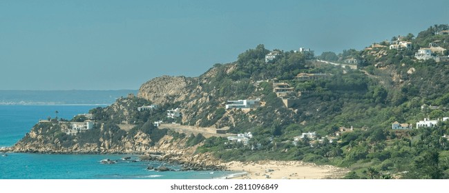 Elevated panoramic view of a sandy beach and turquoise Atlantic waters along the Cadiz coastline in southern Spain.	