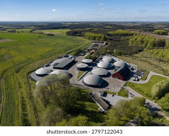 Elevated perspective capturing the layout of a modern bioenergy plant, with a foreground of trees and a background stretching across the rural landscape of Hammel.