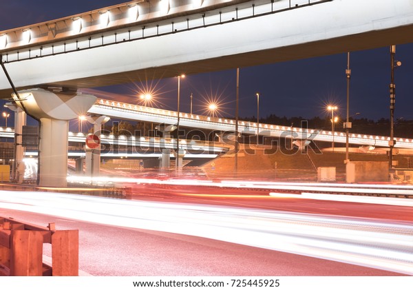 elevated road junction
in the city and interchange overpass at night with motion light
from cars and trucks.