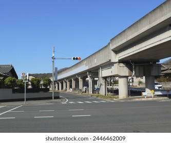 An elevated train runs over the intersection in a Japanese rural town.
Kanji characters on the sign next to the traffic light indicates 'For Pedestrians And Bicycles.'