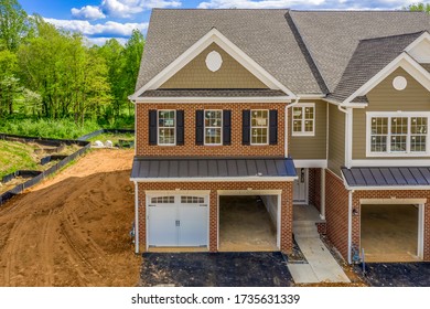 Elevated View Of Almost Finished Luxury Townhouses With Two Single Car Garages, Brick And Shake And Shingle Siding, Gable Roof With Attic Vent On A New Residential Development In Maryland USA