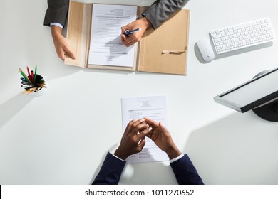 Elevated View Of Businessperson And Candidates Hand With Resume On White Desk - Shutterstock ID 1011270652