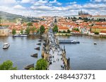 Elevated view of the crowded Charles Bridge and old town of Prague during a sunny summer day, Czech Republic