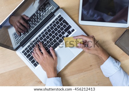 Elevated view of desk with hands on laptop and credit card payment