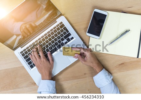 Elevated view of desk with hands on laptop and credit card payment