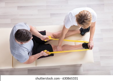 Elevated View Of A Female Physiotherapist Giving Exercise Treatment To Man - Powered by Shutterstock