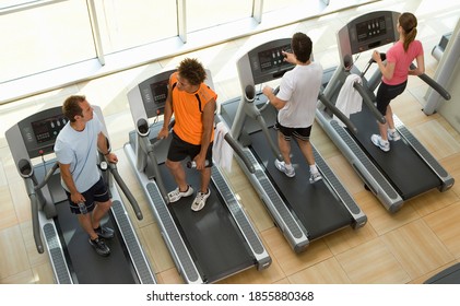 Elevated view of four people on treadmills working out in gym clothes. - Powered by Shutterstock