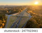 Elevated view of freeway exit junction over road lanes with fast moving traffic cars and trucks at sunrise. Interstate transportation infrastructure in USA