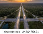 Elevated view of freeway exit junction over road lanes with fast moving traffic cars and trucks at sunrise. Interstate transportation infrastructure in USA