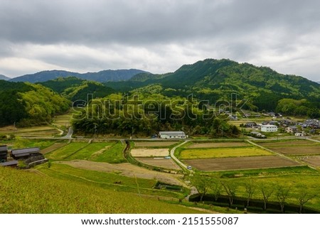Elevated view of grain fields and rural homes nestled in mountains on cloudy day