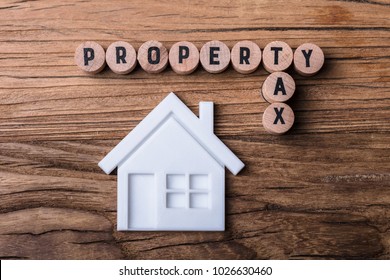 Elevated View Of House Model Near Blocks With Property And Tax Text On Wooden Background