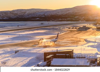 Elevated View Of A Jet Aircraft Being De-iced On The Airport Tarmac At Sunrise, At Alta Airport, With A View Of Snowy Mountains, Winter, Arctic Circle, Alta, Troms Og Finnmark, Norway 03.04.20