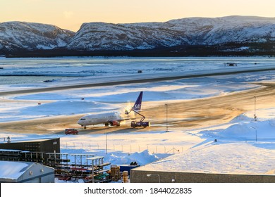 Elevated View Of A Jet Aircraft Being De-iced On The Airport Tarmac At Sunrise, At Alta Airport, With A View Of Snowy Mountains, Winter, Arctic Circle, Alta, Troms Og Finnmark, Norway 03.04.20