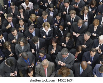 Elevated view of large group of business people text messaging with mobile phones 