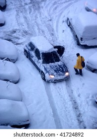 elevated view of man walking snow covered ground and parked cars