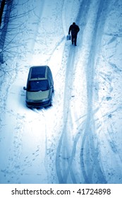 elevated view of man walking snow covered ground and parked car