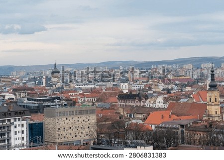 Elevated view over Cluj-Napoca rooftops and church towers under cloudy sky in Transylvania, Romania.