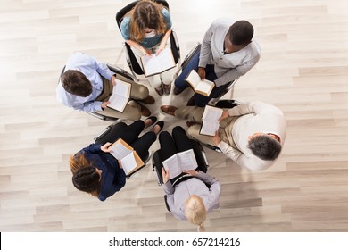 Elevated View Of People Sitting On Chair In Circle Reading Books