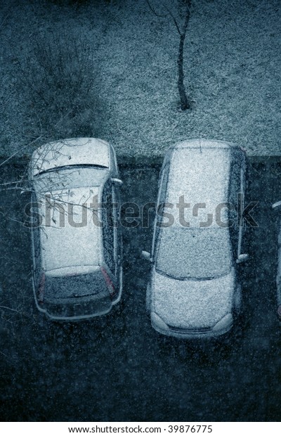 elevated view of\
snow covered cars in parking\
lot