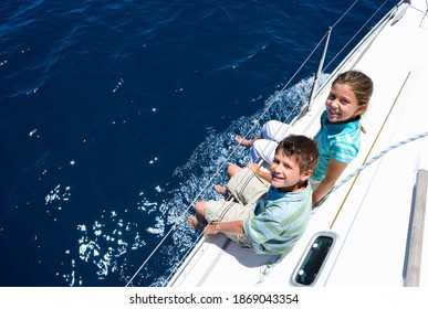 Elevated View Of A Young Boy And Girl Sitting On The Deck Of A Sailing Boat Out To Sea.