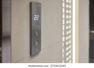 Elevator control panel displaying floor , brushed steel doors, beige wall, illuminated numeric display, round tactile buttons, soft ambient corridor lighting,