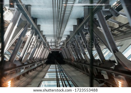 Elevator shaft  interior, view from lift car showing wire rope cables and steel supports with motion blur
