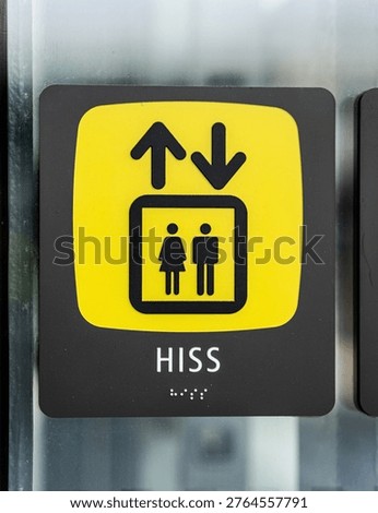 Elevator sign with up and down arrows and accessibility symbol on glass panel