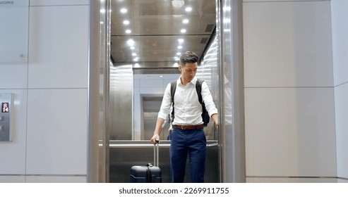 Elevator, travel and watch with a business asian man in an airport, checking the time of his flight for departure. Door, floor and late with a male employee holding suitcase luggage while traveling - Powered by Shutterstock