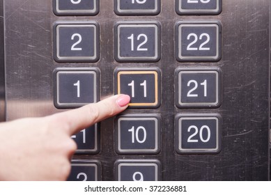 Eleventh (11th) floor elevator button is pushed by a female finger