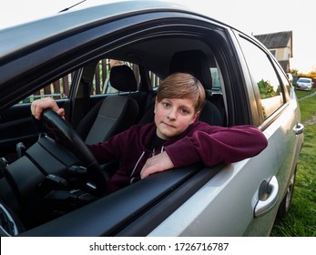 Eleven-year-old Caucasian Boy Sits In The Driver's Seat Before A Study Trip Under The Guidance Of His Father