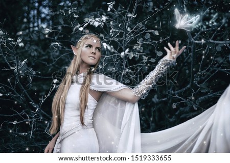 Elf with long white hair in the forest. magical photo shoot. fairy tale. beautiful girl in a white dress. fancy silver accessories