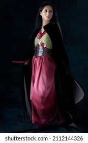 An Elf Warrior Queen Wearing A Laced Bodice And Draped Skirt With A Cloak And Holding A Dagger