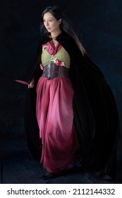 An Elf Warrior Queen Wearing A Laced Bodice And Draped Skirt With A Cloak And Holding A Dagger