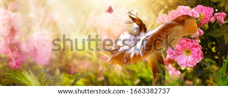 Elf woman in dress and hat sitting on fantasy giant large mushroom releasing butterfly from hand in magical enchanted fairy tale rose flower blooming garden, fairytale floral fabulous background