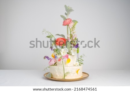 Elite wedding cake with a mix of fresh flowers, many levels, on a light background with space for text. Big stylish wedding cake