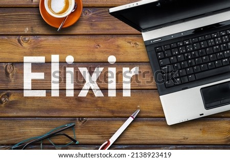 Elixir Programming Language. Word Elixir on wooden desk and laptop
