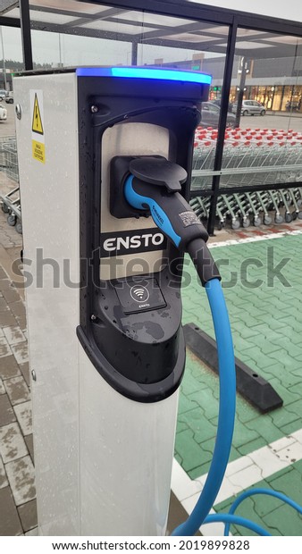 Elk, Poland - July
15, 2021: A static shot of a solid black Tesla Model 3 dual motor
long range awd charging at the ENSTO AC charging station in a rainy
summer evening day