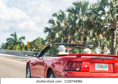 Ellenton, USA - April 27, 2018: Senior couple driving on sports car on road, highway with palm trees in Florida