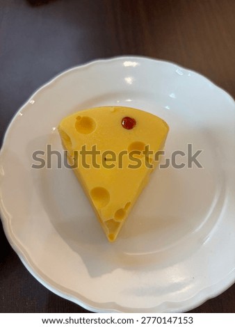 ellow triangular cheesecake with holes inspired by classic cartoon cheese served on a ceramic plate