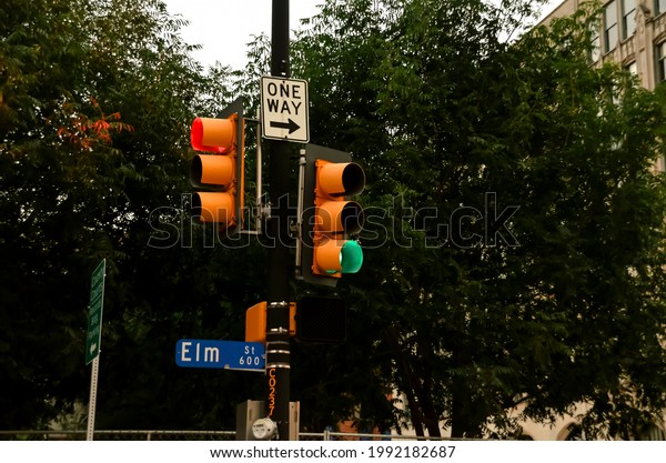 Elm street\
crossing with two traffic lights, a direction sign and a blue\
street sign showing the street\'s\
name.