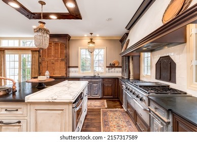 ELMHURST, IL, USA - APRIL 18, 2020: An Italian Inspired Kitchen With Dacor Stainless Steel Stove Appliances, Bar Stools Sitting At The Island, And A Black Granite Counter Top.