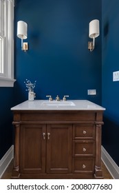 ELMHURST, IL, USA - AUGUST 1, 2020: A Blue Bathroom With A Wooden Vanity Cabinet, Lights Mounted On The Wall, And A White Granite Countertop.