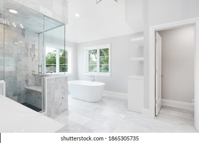 ELMHURST, IL, USA - AUGUST 17, 2019: A Large Luxurious Bathroom With A Stand Alone Tub, White Vanity, And A Glass Stand Up Shower With Marble Tiles And Bench Seat.