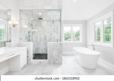 ELMHURST, IL, USA - AUGUST 17, 2019: A Large Luxurious Bathroom With A Stand Alone Tub, White Vanity, And A Glass Stand Up Shower With Marble Tiles And Bench Seat.