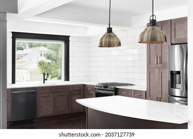 ELMHURST, IL, USA - AUGUST 3, 2021: A Beautiful Renovated Kitchen With Dark Wood Cabinets, Stainless Steel Appliances, White Granite Countertops, And A White Subway Tile Backsplash.