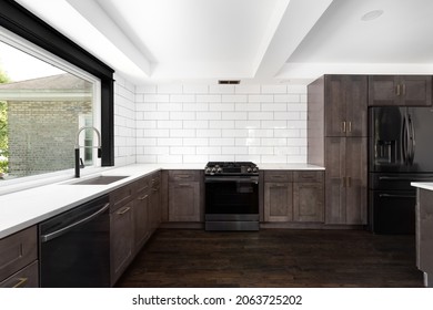 ELMHURST, IL, USA - AUGUST 3, 2021: A Beautiful Renovated Kitchen With Dark Wood Cabinets, Stainless Steel Appliances, White Granite Countertops, And A White Subway Tile Backsplash.